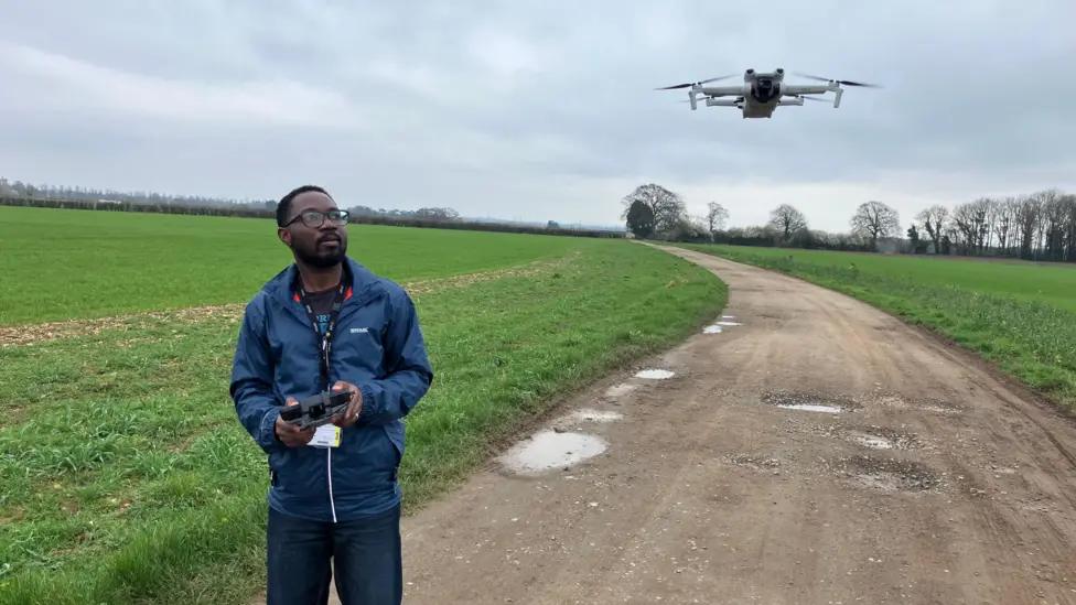 Emmanuel flying a drone over farmland