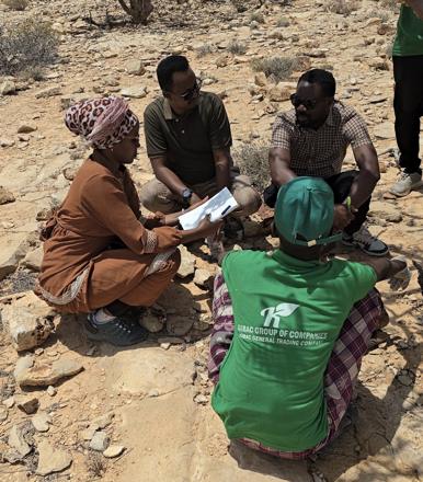 Emmanuel interviewing frankincense workers in rocky scrubland